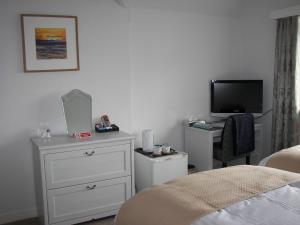 a bedroom with a bed and a dresser and a tv at Seaways Cottage Hoylake in Hoylake