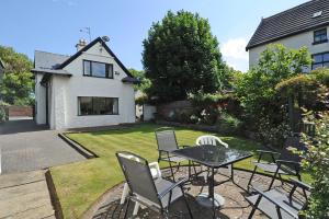 a patio with chairs and a table in a yard at Seaways Cottage Hoylake in Hoylake