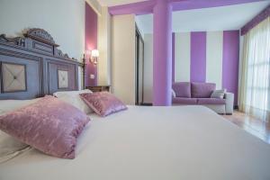 
a bed room with a white bedspread and pillows at Hotel Rosaleda Don Pedro in Úbeda
