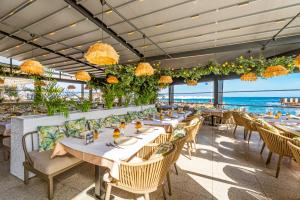 a restaurant with tables and chairs with the ocean in the background at Kaya Palazzo Resort & Casino in Kérynia