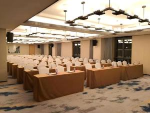 a large room with rows of tables and white chairs at Zhuhai Tangyi Hotel in Tongka