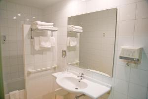 Baño blanco con lavabo y espejo en Hotel Balaguer, en Balaguer