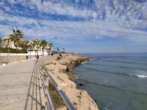 Una pasarela junto al mar con palmeras. en La Florida Catalina House, en Orihuela Costa