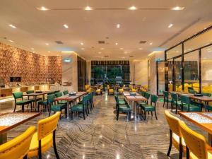 a restaurant with wooden tables and green chairs at Zmax Hotel Guangzhou Railway Station in Guangzhou