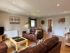 Bluebell Lodge 5 with Hot Tub في نيوتن ستيوارت: غرفة معيشة بها أريكة وطاولة
