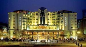 a large building with cars parked in a parking lot at Haihua Hotel Hangzhou in Hangzhou