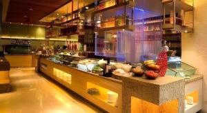 Ramada by Wyndham Zibo في تزيبو: امرأة تقف وراء منضدة في مطبخ