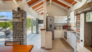 a kitchen with white cabinets and a dining table at Rustic villa Inga with pool and grill in Buje in Kaštel