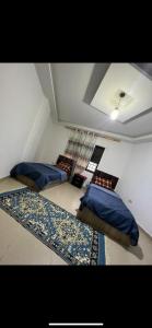3 camas en una habitación con almohadas azules y alfombra en ardan, en Amán 3 fotos más