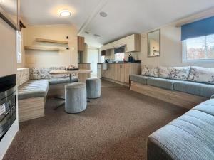 a living room with couches and a table and a kitchen at Jordana Lodge in Edzell