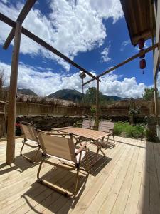 a wooden deck with a table and chairs on it at Siguniang Mountain Lanxi Wild Luxury Hotel in Mount Siguniang