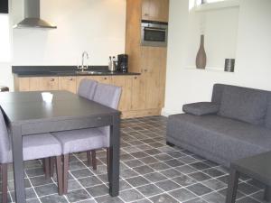 cocina y sala de estar con mesa y sofá en De Zandkant, en Biezenmortel