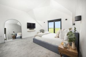 Copper Tree في Cubert: غرفة نوم بيضاء مع سرير كبير ومرآة