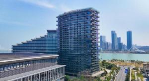 Huafa Executive Apartment Hotel Zhuhai في Cheoc Ca Chün: مبنى طويل مع مدينة في الخلفية