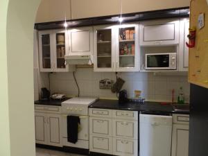 a kitchen with white cabinets and white appliances at Sissy Apartment in Budapest