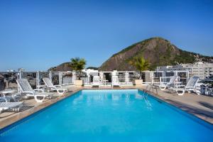 a swimming pool on the roof of a building with chairs at Hotel Atlântico Copacabana in Rio de Janeiro