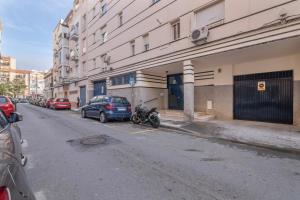 una calle con coches aparcados al costado de un edificio en Grey House, en Huelva