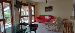 a living room with a red couch and a glass table at Praia Brava Apto 2 dorms Vista ao Mar in Florianópolis