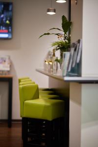Una fila de taburetes verdes sentados en una barra en ante porta DAS STADTHOTEL, en Trier