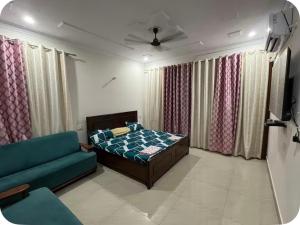 a bedroom with a bed and a couch and curtains at Himshikha Colony 2bhk in Surajpur