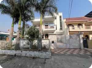 a white house with palm trees in front of it at Himshikha Colony 2bhk in Surajpur