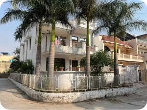 a white house with palm trees in front of it at Himshikha Colony 2bhk in Surajpur