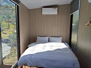 a bed in a room with a large window at Forest Star Cottage X by Tiny Away in Hsin-ch'eng