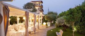 eine Terrasse mit weißen Tischen und Stühlen und ein Gebäude in der Unterkunft Hotel Villa Clementina in Scafati