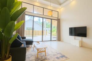 a living room with a couch and a table at Cocolane Villa 2 in Ban Madua Wan