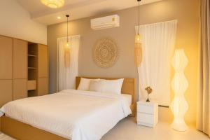 a bedroom with a bed with white sheets and a window at Cocolane Villa 2 in Ban Madua Wan