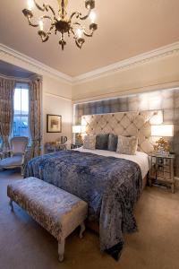 a large bedroom with a large bed and a chandelier at Trinity Boutique B&B in Peterhead