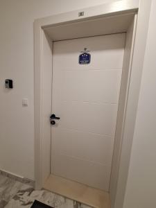 a white door with a blue sign on it at Apartman MILOVANOVIĆ in Vrnjačka Banja