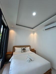 a bedroom with a white bed with a towel on it at Kariarta Homestay in Cemagi +3 photos