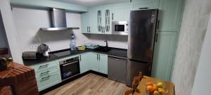 Una cocina con gabinetes verdes y electrodomésticos de acero inoxidable. en Casa Rural Emma, en Zuheros