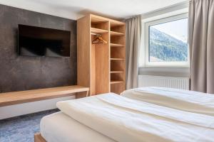 Un dormitorio con dos camas y un televisor y una ventana. en Maurig Appartements, en Elbigenalp