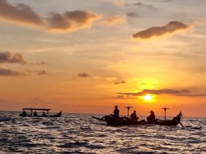people in boats in the ocean at sunset at Kariarta Homestay in Cemagi