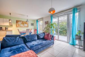 a living room with a blue couch and a kitchen at Bright house ideal for exploring Bordeaux in Bordeaux