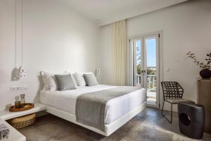 a white bedroom with a bed and a balcony at Manesis Suites in Pollonia +114 photos