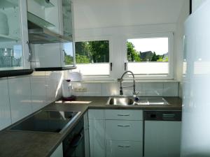 a white kitchen with a sink and two windows at Ferienwohnung Schuberski in Lipperreihe