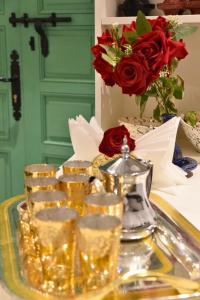 マラケシュにあるRiad Lilou Marrakechのグラスが置かれたテーブルとバラの入った花瓶 +49枚の写真