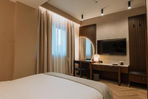 ブカレストにあるホテル トリアノンのベッドと机とテレビがあるホテルの部屋