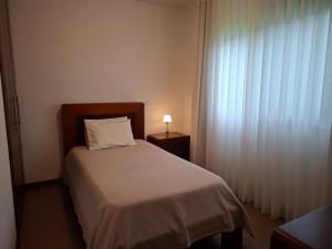 Un dormitorio con una cama y una lámpara sobre una mesa. en Sítio da Assumada, en Faja Grande