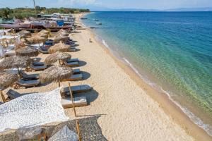 una spiaggia con sedie e ombrelloni e l'oceano di Elektra Comfort Hotel by Del Mare a Skala Prinos