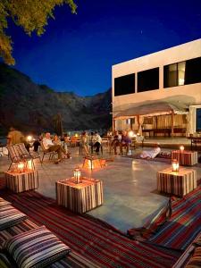 a group of people sitting on a patio at night at Wadi Al Arbeieen Resort in Ḑibāb