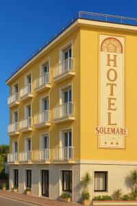 Hotel SoleMare في ديانو مارينا: مبنى اصفر عليه علامة الفندق