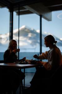 two women sitting at a table in front of a window at LH Linzerhaus Suites Saalbach - inklusive Jokercard in Saalbach-Hinterglemm