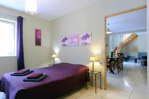een slaapkamer met een paars bed en een eetkamer bij Cecile in Montgaillard