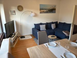 a living room with a blue couch and a tv at Wohnung HaHü in Dangast