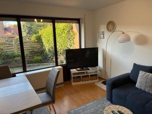 a living room with a tv and a blue couch at Wohnung HaHü in Dangast