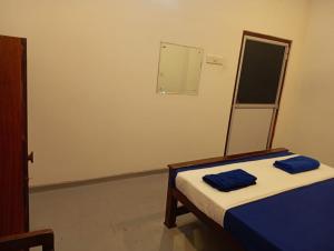 a bedroom with a bed with two blue towels on it at Kenashi Green Villa in Weligama